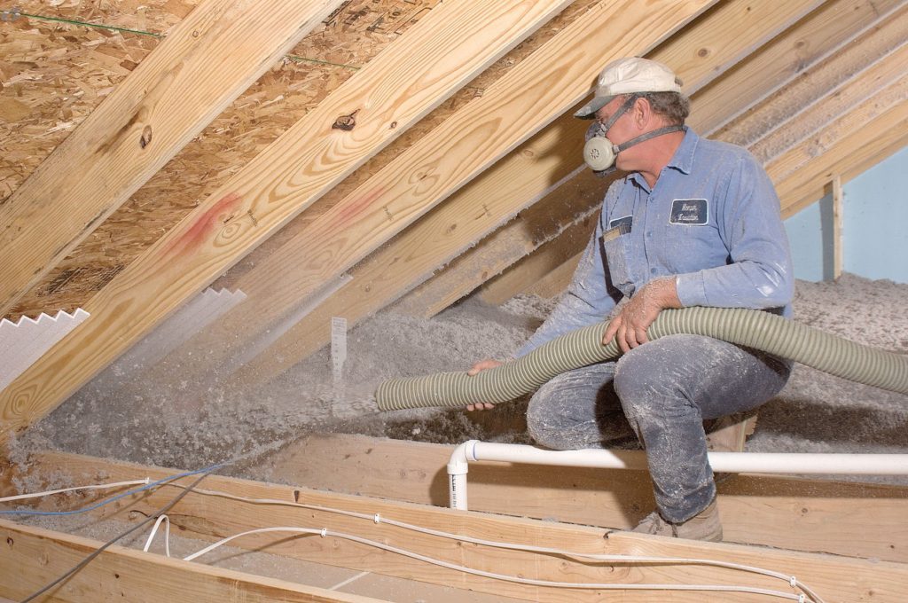 Technician installing insulation in an attic