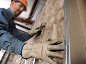 Technician installing batt insulation in a wall