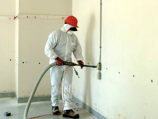 Worker re-insulating a wall using drill and fill insulation. 