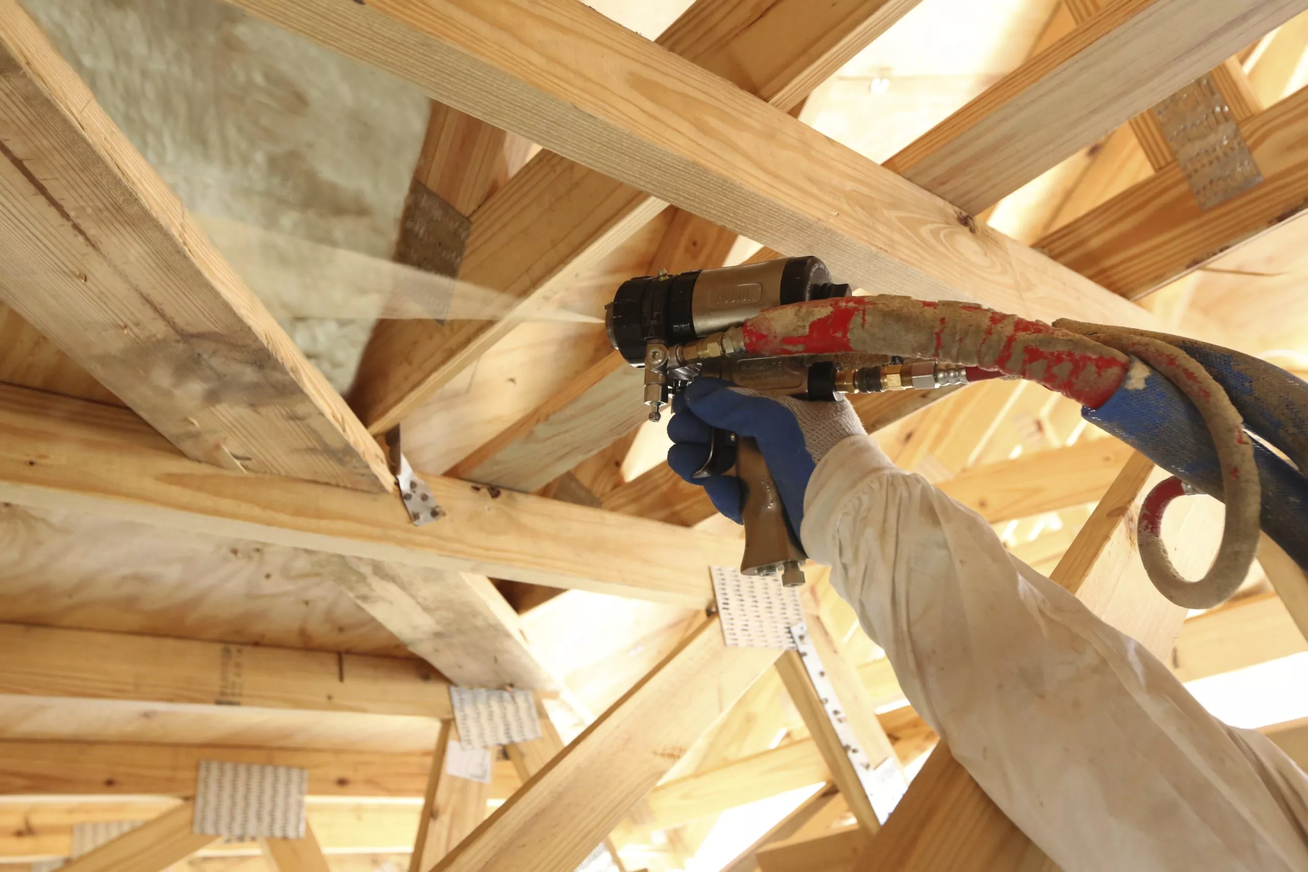 Contractor applying spray foam insulation in new construction